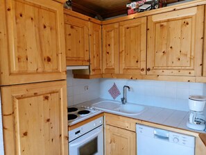 Eine Küche mit Holzschränken, einem Herd, einer Spüle und einem Geschirrspüler.