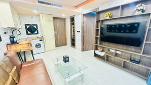 Una sala de estar moderna con un sofá, una mesa de centro de vidrio, un televisor y un estante de madera empotrado.