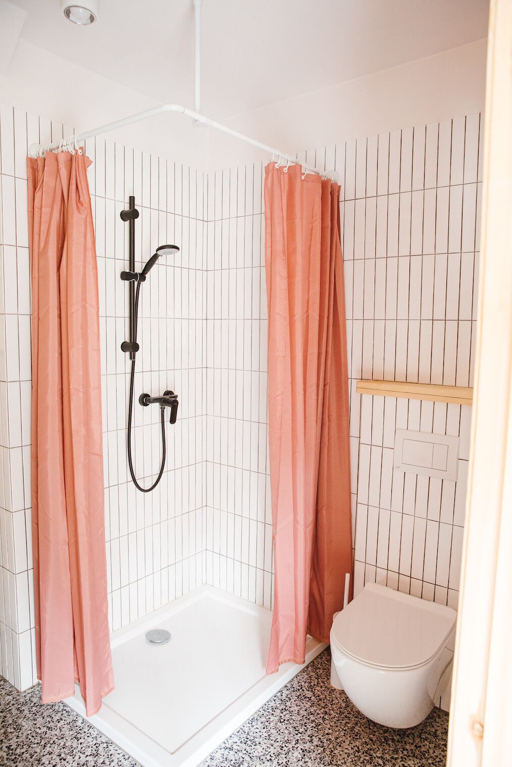 Een badkamer met douche, toilet en betegelde wanden.