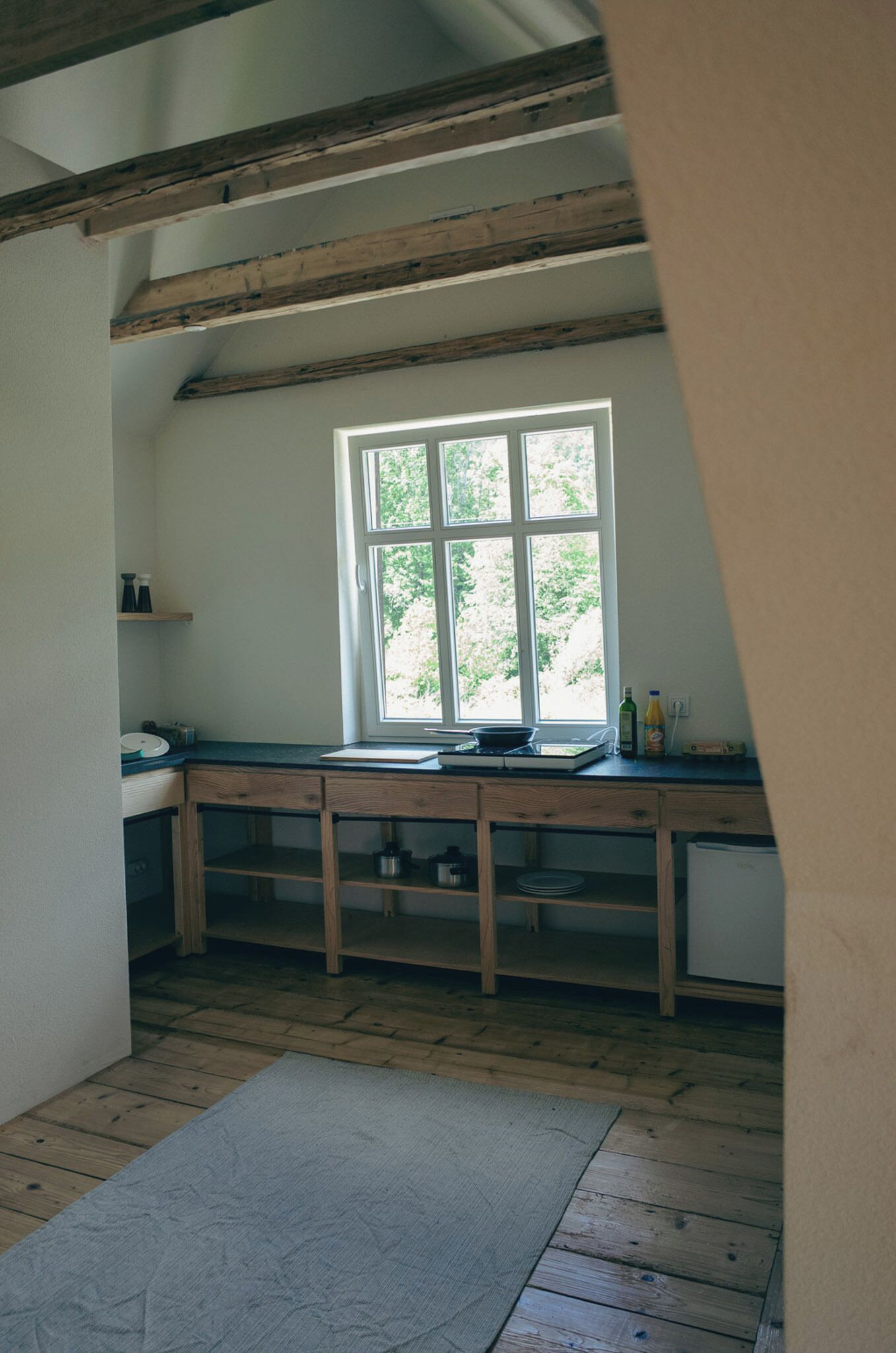 A kitchen with wooden beams, a window, and a countertop with kitchen items.