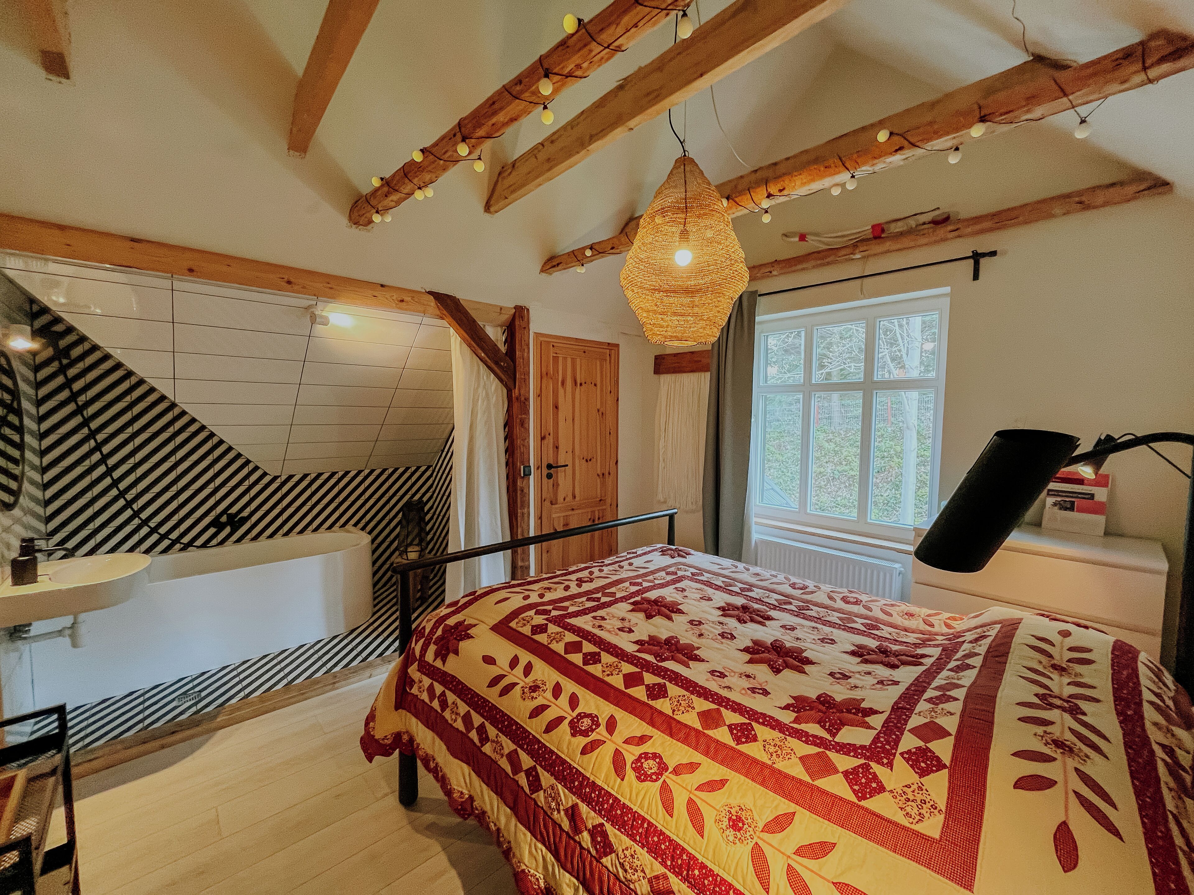 Un dormitorio con cama, ventana, escalera y baño.