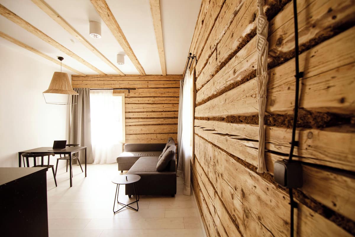 A modern room with wooden walls, a sofa, a dining table, and a laptop.
