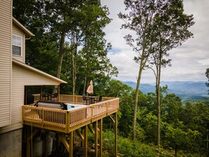 A wooden deck with outdoor furniture, overlooking a forested landscape with distant mountains. - 4000ft Elevation w Miles of Views from Angel Ridge with Hot Tub & Expansive Deck (Waynesville)
