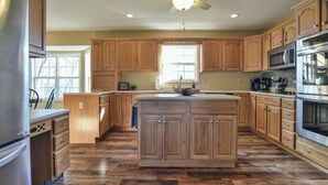 Una cocina con armarios de madera, una isla central y un ventanal grande.