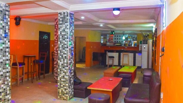 Una zona de bar con taburetes, mesas y una barra.