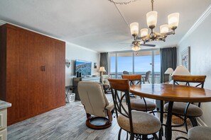 Un coin repas comprenant une table ronde et six chaises, un buffet en bois et un ventilateur de plafond avec éclairage.