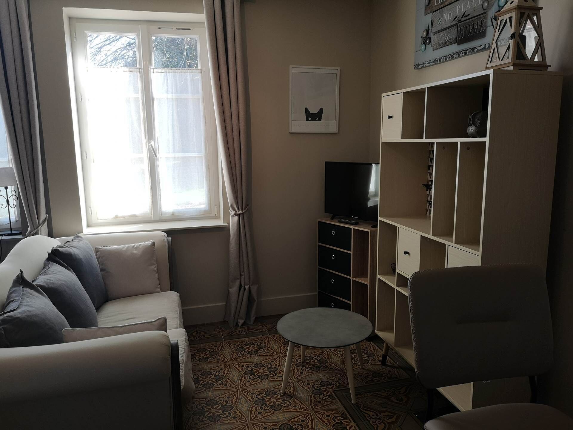 Een woonkamer met een bank, een bijzettafeltje, een televisie en een kast.