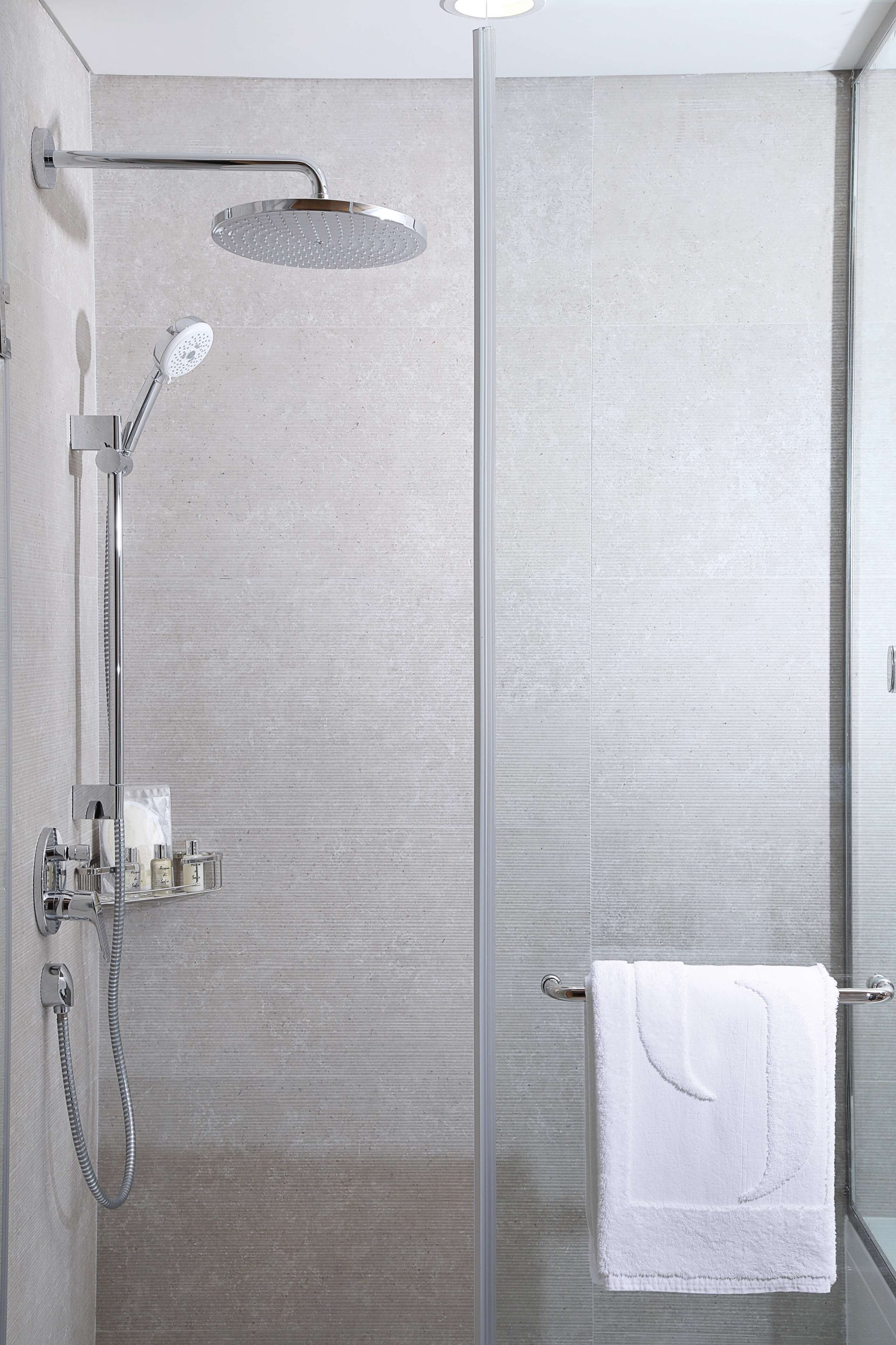 A modern shower with a handheld showerhead and a wall-mounted rain showerhead.