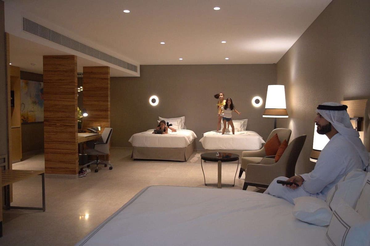 Une chambre d’hôtel avec deux lits, un bureau, une chaise et un canapé.