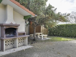 A patio with a built-in grill, outdoor seating, and a tree. - Cozy Beach House: Steps from Center, 400m to Ocean, Sleeps 6 (Biscarrosse Plage)
