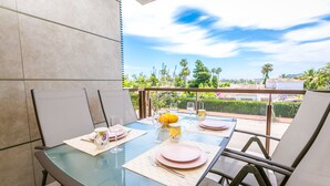 A glass-top dining table with chairs, set with pink plates, glasses, and a fruit bowl. - Apartment Lychee - Golden Star Javea close to Arenal beach. (Xàbia)