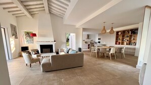 Un vaste espace de vie doté d’une cheminée, d’une table à manger avec des chaises et d’une cuisine à l’arrière-plan.