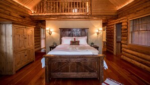 Quarto de cabana de madeira com cama de madeira, duas luminárias de cabeceira, uma cabeceira de madeira e uma varanda.