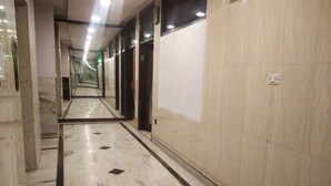 Un pasillo con suelo de mármol, paredes espejadas y varias puertas.