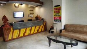 Zona de recepción con mostrador de mármol, un sofá y un televisor.