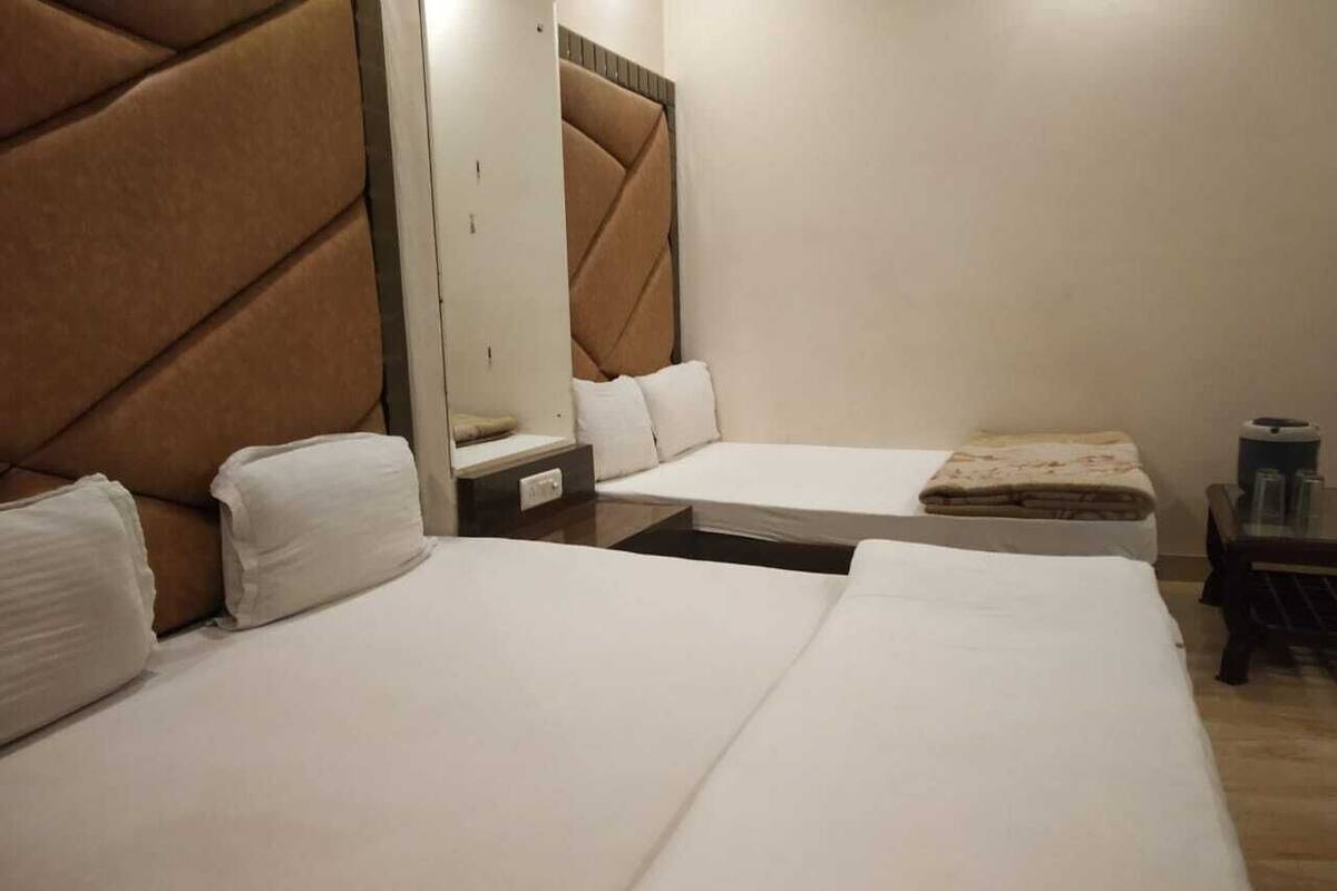 A hotel room with two beds, a large mirror, and a small table with a lamp.