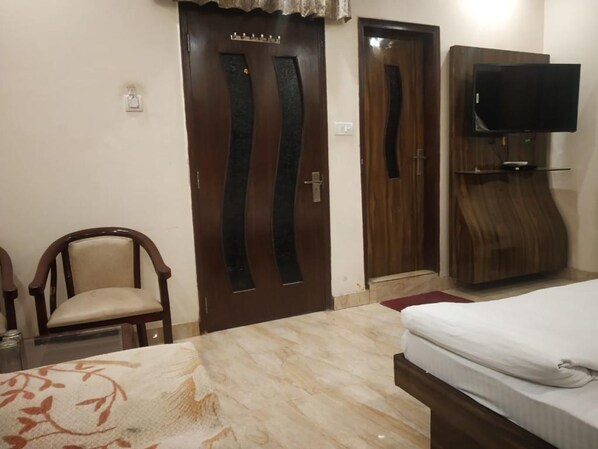 Un dormitorio con cama, un armario de madera, un televisor en la pared y una silla.