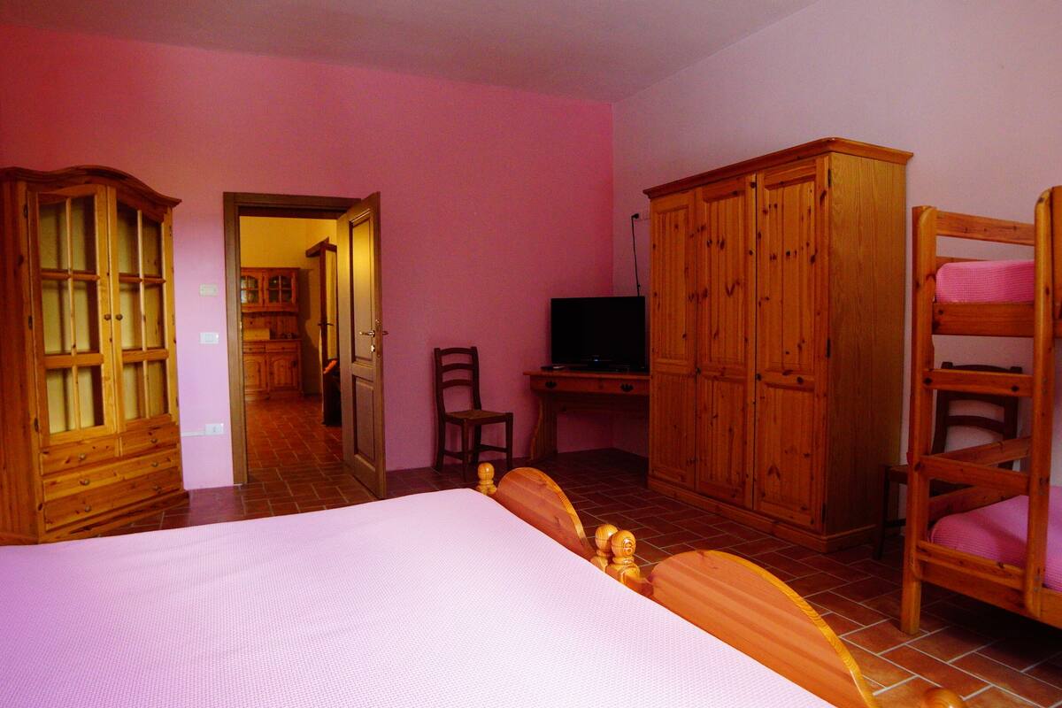 Ein Schlafzimmer mit Bett, Holzschrank, Fernseher und Stuhl.