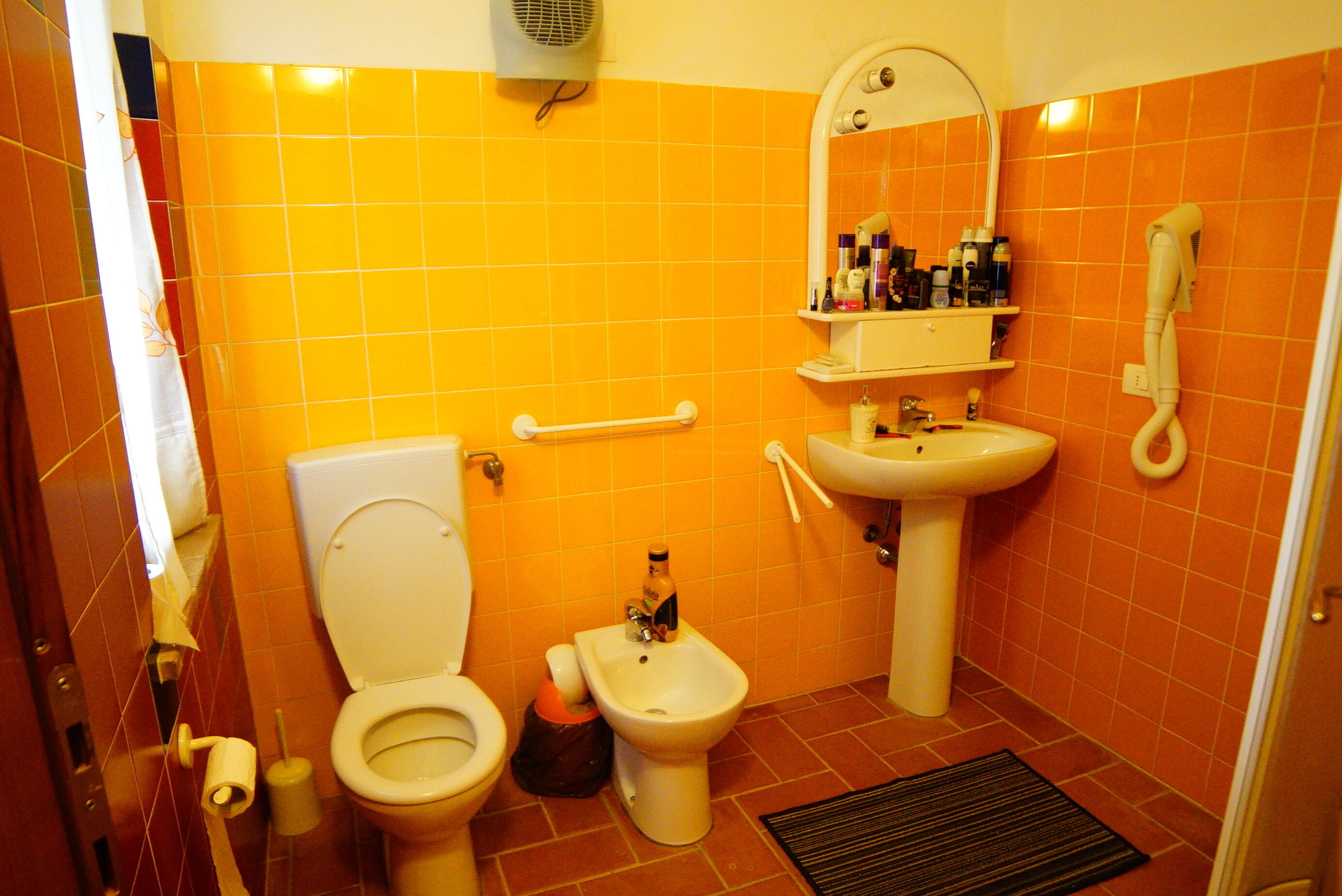 A bathroom with a toilet, bidet, sink, and a mirror above the sink.
