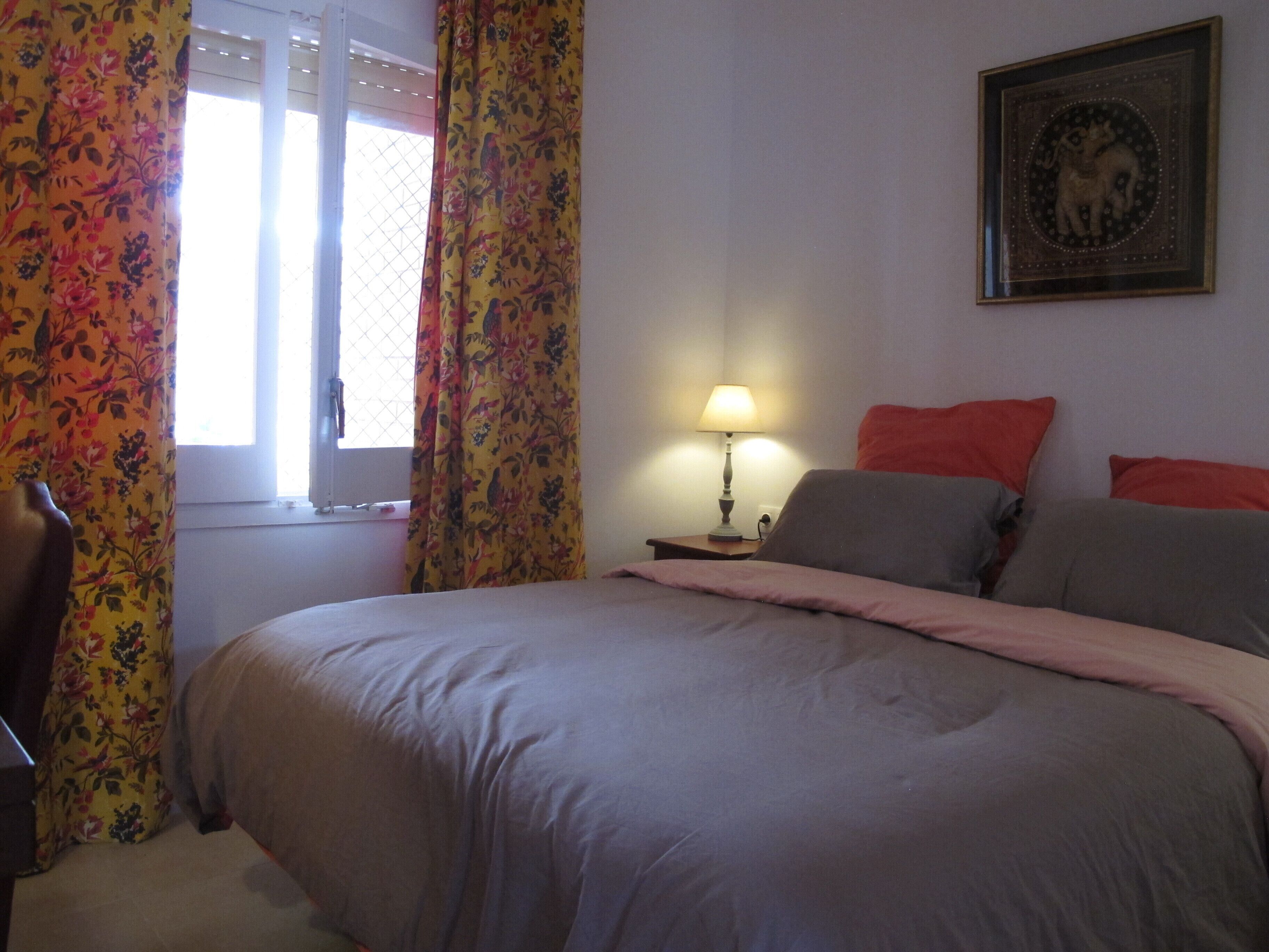 A bedroom with a bed, a nightstand, a lamp, and a framed picture on the wall.