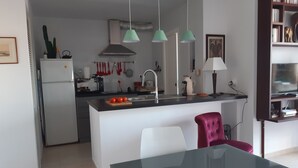 Una cocina moderna con una isla central, una mesa de comedor y una silla roja.