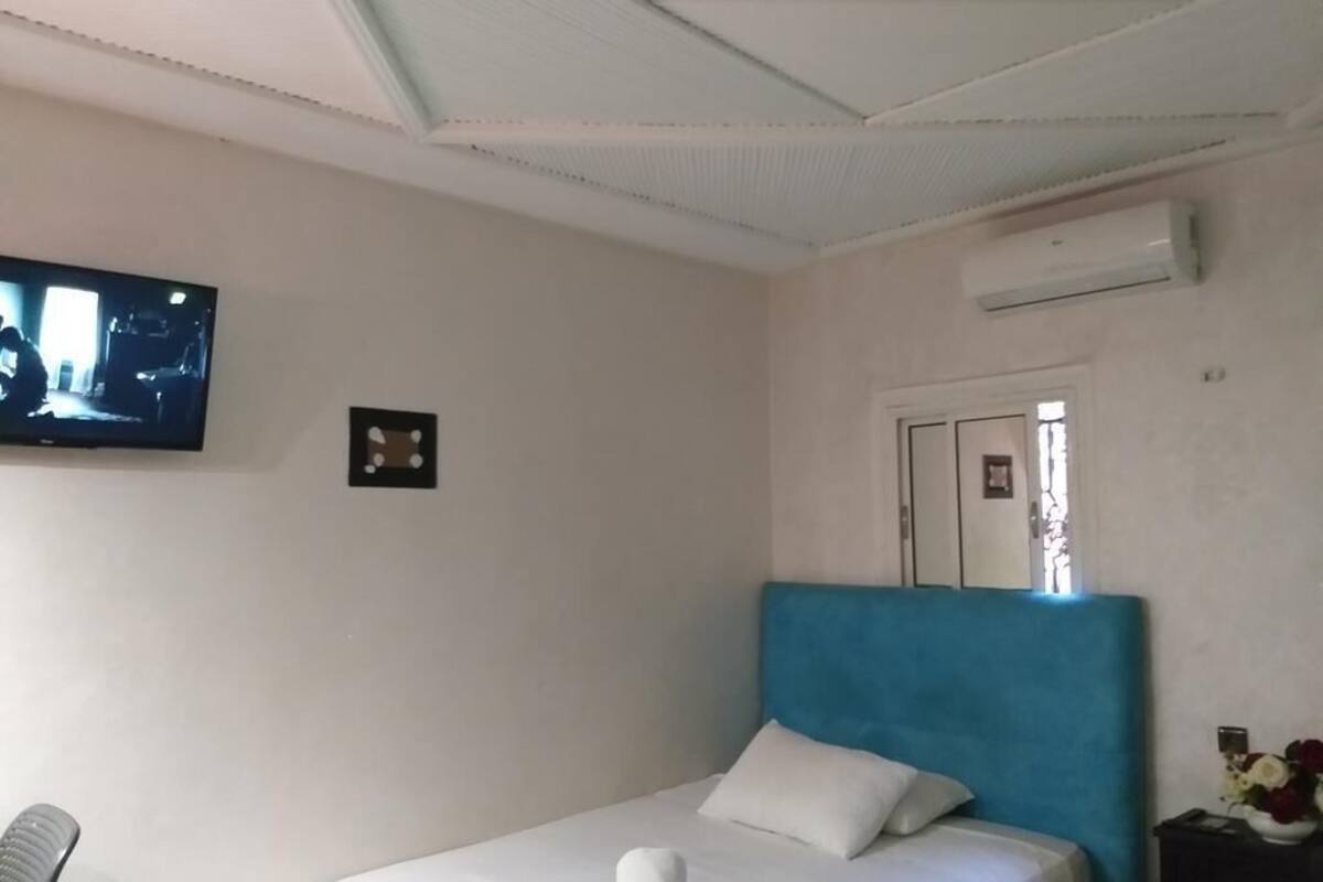 Un dormitorio con una cama, un televisor montado en la pared y un equipo de aire acondicionado.