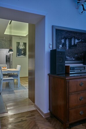 A modern living room with a wooden cabinet, a television, and a dining area with a table and chairs. - Live in one of the most beautiful tenements in Krakow.  (Stare Miasto)