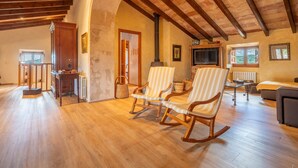 Un'ampia zona giorno con pavimento in legno, camino, televisione e poltrone a dondolo a righe.
