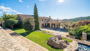 Un cortile con un vialetto in pietra, una piscina e un edificio con tetto in tegole.