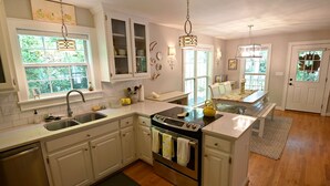 Una cocina con armarios blancos, una estufa de acero inoxidable y un ventanal grande.