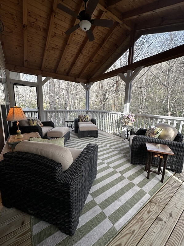 A covered porch with wicker furniture, a ceiling fan, and a checkered floor.