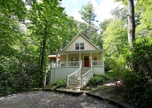 A two-story house with a red door, a front porch, and a staircase leading to the entrance.
