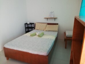 Un dormitorio pequeño y ordenado con una cama individual, una mesita de noche, una estantería y una silla.