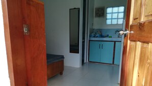 A room with a bed, a window, a mirror, and a kitchenette with cabinets and a sink. - Siargao Hannah House (Surigao city)