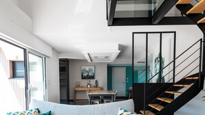A modern living room with a sofa, a wooden coffee table, and a staircase with a glass railing. - Air-conditioned house on the Rhuys peninsula with Jacuzzi (Saint-Gildas-de-Rhuys)