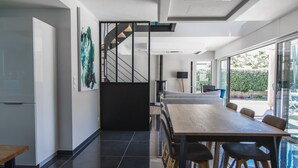 A modern kitchen with a large island, dark tiled flooring, and a staircase leading to an upper level. - Air-conditioned house on the Rhuys peninsula with Jacuzzi (Saint-Gildas-de-Rhuys)