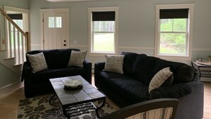 A living room with two dark-colored sofas, a coffee table, and a patterned rug. - Newly built and fresh vacation home tucked in the woods of Mount Desert.  (Mount Desert)