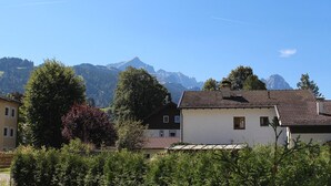Un pueblo de montaña con casas tradicionales, cielo despejado y una cordillera al fondo.
