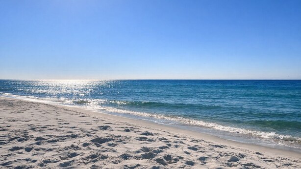 A beach with clear skies and sunlight reflecting off the water. - Sea Oats I-202. Pool View, Waterfront Access. 1K, 2Q, 1Q sofa bed. (Gulf Shores)
