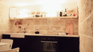 A kitchen with a stone wall, a wooden countertop, a kettle, and a sink. - CASA NAUTILO - A terrace with a Sea (Monopoli)
