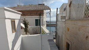 A narrow alleyway with a stone floor, white buildings, and a view of the sea and a bridge in the distance. - CASA NAUTILO - A terrace with a Sea (Monopoli)