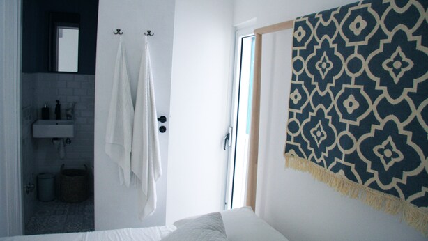 A bedroom with a bed, a bathroom with a sink and mirror, and a patterned wall hanging. - CASA NAUTILO - A terrace with a Sea (Monopoli)