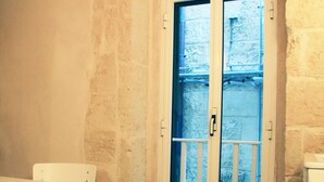 A room with a white table and chair, a light bulb hanging from the ceiling, and a door leading to an outdoor area. - CASA NAUTILO - A terrace with a Sea (Monopoli)