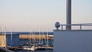 A marina with multiple sailboats docked, a building with a spherical ornament on top, and a clear view of the water and sky. - CASA NAUTILO - A terrace with a Sea (Monopoli)