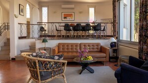 A spacious living room with a brown leather sofa, a wicker chair, and a dining area with a table and chairs. - Villa in front of old port Golfe-Juan. Sea view, walk to beach, restaurants. AC! (Vallauris)