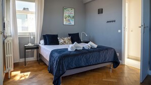 A bedroom with a bed, a bedside table, a radiator, and a window with curtains. - Villa in front of old port Golfe-Juan. Sea view, walk to beach, restaurants. AC! (Vallauris)