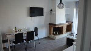 A modern dining area with a fireplace, a flat-screen TV mounted on the wall, and a dining table set for two. - modern, newly renovated apartment in Cabo Roig, beach within walking distance (Orihuela)