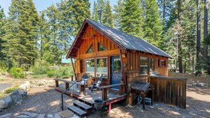 Eine rustikale Holzhütte mit Veranda, einer Holzterrasse und einem Kiesweg.