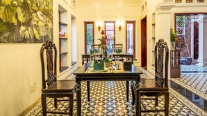 A dining area with a table set for four, flanked by ornate chairs, a large floral painting, and a patterned floor. - Paddy Home (Cam Pha)