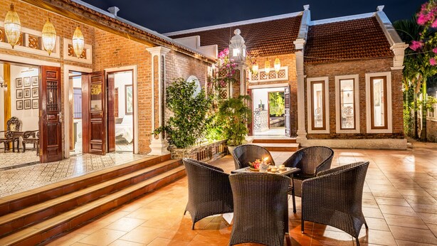 A courtyard with wicker furniture, a brick building, and decorative lighting. - Paddy Home (Cam Pha)